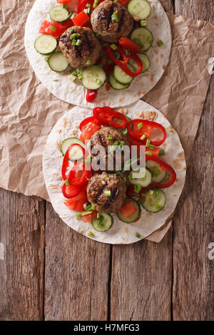 Gegrillte Frikadellen mit frischem Gemüse auf ein flaches Brot auf dem Tisch. Vertikale Ansicht von oben Stockfoto