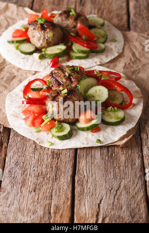 Gegrillte Frikadellen mit frischem Gemüse auf ein flaches Brot hautnah auf dem Tisch. Vertikal Stockfoto