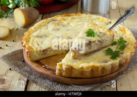 Eine klassische Quiche Lorraine-Torte mit Kartoffeln, Fleisch und Käse auf einem Holztisch. Platz für Ihren Text. Stockfoto