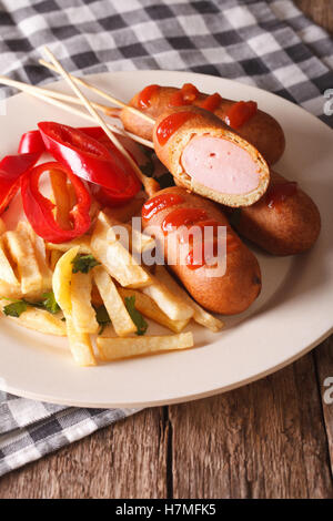 Corndog, Pommes Frites und Gemüse auf einer Platte Nahaufnahme auf dem Tisch. Vertikal Stockfoto