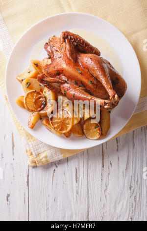 Zitronen-Huhn mit Kartoffeln garniert auf einem Teller auf den Tisch. vertikale Ansicht von oben Stockfoto