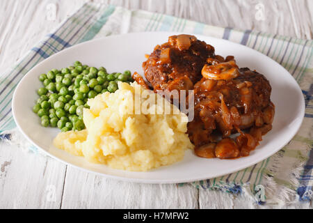 Salisbury Steak mit Kartoffeln und Erbsen-close-up auf einem Teller auf den Tisch. horizontale Stockfoto