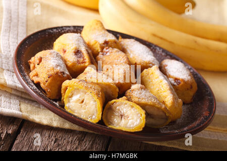 Leckere gebratene Bananen im Teig bestreut mit Puderzucker Nahaufnahme auf dem Tisch. Horizontale Stockfoto