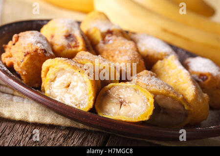 Gebratene Bananen in Teig bestreut mit Puderzucker Nahaufnahme auf einem Teller auf den Tisch. horizontale Stockfoto