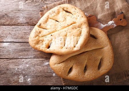 Fugasse französisches Brot mit Sesam-Samen und Kräuter-Closeup auf dem Tisch. Horizontale Ansicht von oben, rustikal Stockfoto