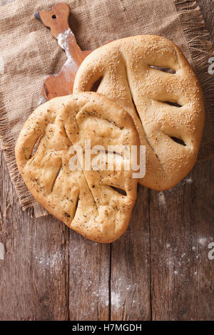 Fugasse französisches Brot mit Sesam-Samen und Kräuter-Closeup auf dem Tisch. Vertikale Ansicht von oben, rustikal Stockfoto