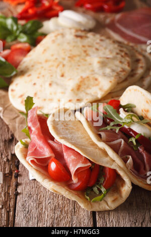 Italienische Piadina Fladenbrot gefüllt mit Schinken und Gemüse Nahaufnahme auf dem Tisch. Vertikal Stockfoto