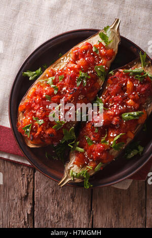 halbe gebackene Aubergine mit Gemüse Nahaufnahme auf einer Platte. vertikale Ansicht von oben Stockfoto