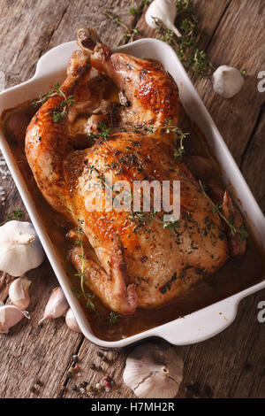 Huhn mit 40 Knoblauchzehen in der Schale zum Backen von Close-up auf dem Tisch. vertikale Stockfoto