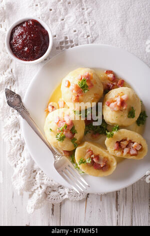 Kartoffelknödel mit Speck Nahaufnahme auf einer Platte-Preiselbeer-Sauce. vertikale Ansicht von oben Stockfoto