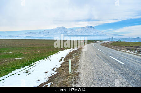 Die Autobahn, umgeben von Ackerland und führt zu Hasan Berg bedeckt mit Schnee, Kappadokien, Türkei. Stockfoto