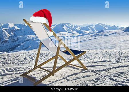 Weihnachtsmütze auf einem Liegestuhl auf der Seite eine Ski-Hang, verschneite Berglandschaft Stockfoto