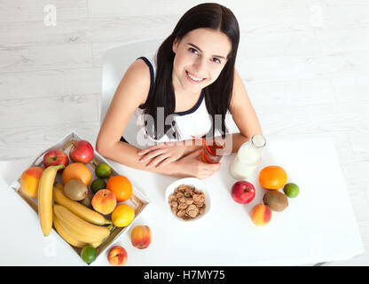 Schöne Frauen gibt es mit reiner Haut im Gesicht, an einem Tisch sitzen und frühstücken. Asiatische Frau gesunde Ernährung beim Frühstück. Obst, Müsli und Milch. Ungewohnter Anblick, Ansicht von oben, selektiven Fokus Stockfoto