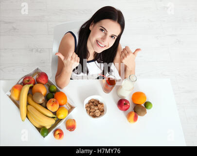 Schöne Frauen gibt es mit reiner Haut im Gesicht, an einem Tisch sitzen und frühstücken. Asiatische Frau gesunde Ernährung beim Frühstück. Obst, Müsli und Milch. Ungewohnter Anblick, Ansicht von oben, selektiven Fokus Stockfoto