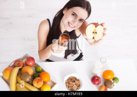 Schöne Frauen gibt es mit reiner Haut im Gesicht, an einem Tisch sitzen und frühstücken. Asiatische Frau gesunde Ernährung beim Frühstück. Obst, Müsli und Milch. Stockfoto