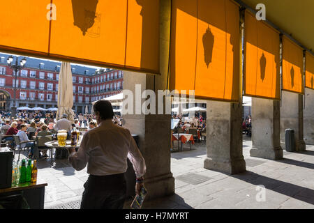 Ein Kellner trägt Getränke Café-Tischen auf der Plaza Mayor im Zentrum von Madrid, Spanien Stockfoto