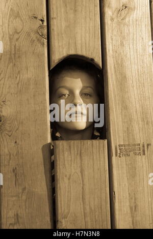 Kleines Mädchen Blick durch Fenster in Holz Schieber Stockfoto