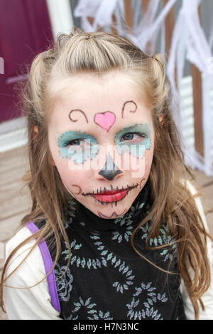 Junges Mädchen mit Sugar Skull Halloween Make-up im Gesicht sitzen auf hölzernen Stufen lackiert Stockfoto