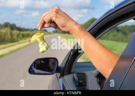 Weiblichen Arm werfen Obst Müll aus Autofenster Stockfoto