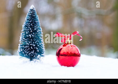 Kleiner Weihnachtsbaum und roten Ball draußen im Schnee Stockfoto