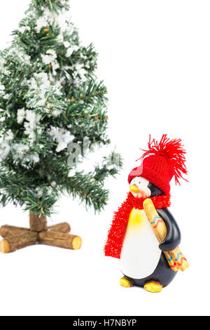 Pinguin Figur mit roter Mütze Schal Ski und Weihnachtsbaum auf weißem Hintergrund Stockfoto