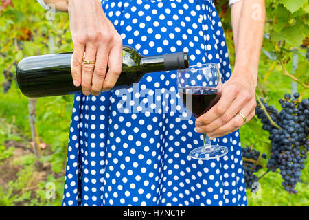 Frau im Weinberg Gießen rote Flasche Wein im Glas Stockfoto