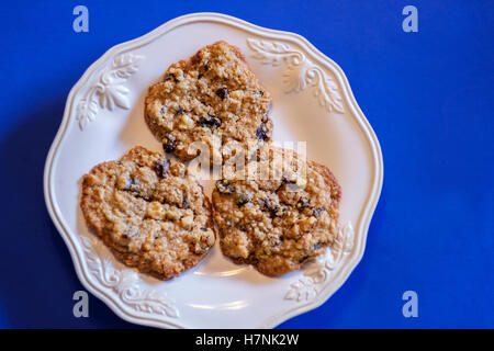 Hausgemachte Haferflocken Rosinen Cookies mit Walnüssen auf einer weißen Platte, blauen Hintergrund. USA Stockfoto