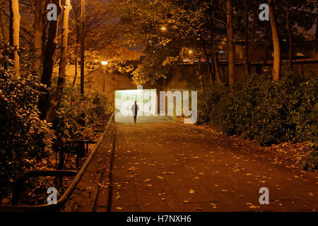 allein junge Mädchen zu Fuß unter Bäume Herbst auf der Straße spät in die Nacht Stockfoto