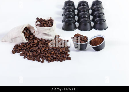 Kapseln von gemahlenem Kaffee für Kaffee, geröstete Kaffeebohnen in einem Lappen-Beutel, gerösteten Kaffeebohnen auf weißem Hintergrund. Stockfoto