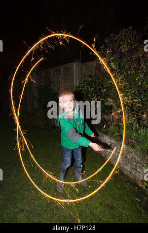 Junge (5 Jahre) im Vorort Hofblick mit handgeführten Feuerwerk Typ "Wunderkerze" Bonfire Night oder traditionell Kerl Fawkes Nacht. Stockfoto