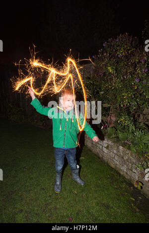 Junge (5 Jahre) im Vorort Hofblick mit handgeführten Feuerwerk Typ "Wunderkerze" Bonfire Night oder traditionell Kerl Fawkes Nacht. Stockfoto