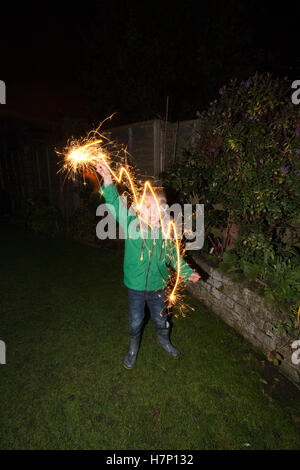 Junge (5 Jahre) im Vorort Hofblick mit handgeführten Feuerwerk Typ "Wunderkerze" Bonfire Night oder traditionell Kerl Fawkes Nacht. Stockfoto