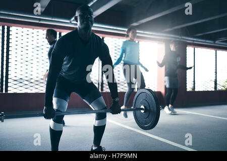 Schwarzer Mann Ausübung anhebende Gewicht Workouts mit Freunden im urbanen Umfeld Stockfoto