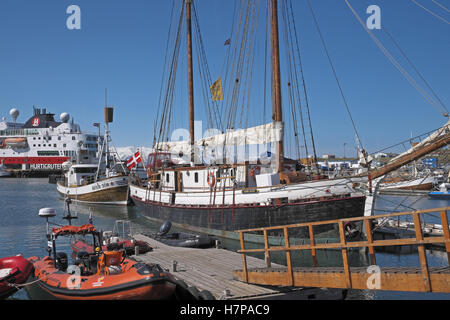 Alte hölzerne traditionelles Segelschiff mit modernen Stahl Kreuzfahrt Schiff jenseits und Schlauchboot Zodiac im Vordergrund, Husavik, Island. Stockfoto