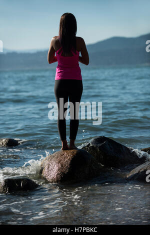 Rückansicht der Frau, die Durchführung von Yoga auf Felsen Stockfoto