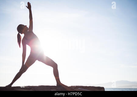 Frau, die Durchführung von Yoga auf Treibholz Stockfoto