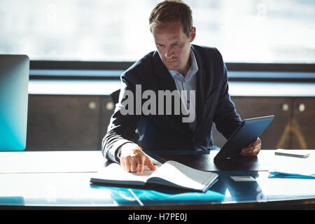 Geschäftsmann, Prüfung sein Tagebuch während der Verwendung von digital-Tablette Stockfoto