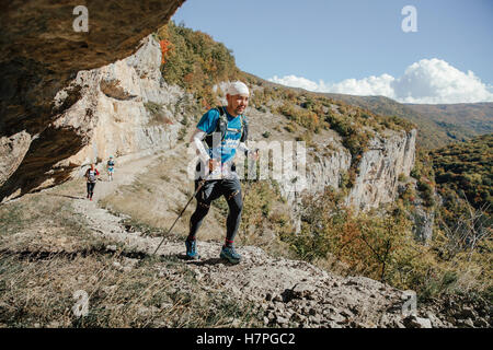 junge männliche asiatische Rasse Athlet mit walking-Stöcken laufen Trail während Crimea Bergmarathon Stockfoto