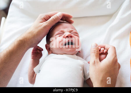 Nicht erkennbare Vater streicheln neugeborenen Sohn zu weinen Stockfoto