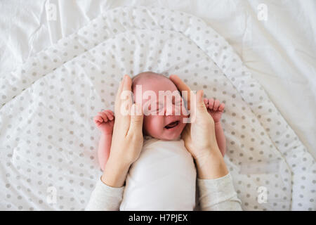 Nicht erkennbare Mutter streichelt neugeborenen Sohn zu weinen Stockfoto