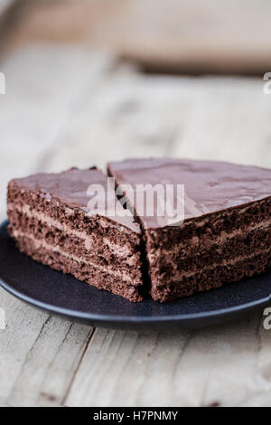 Schneiden von Schokolade Torte mit Schokocreme und Glasur. Hölzerne Hintergrund Stockfoto