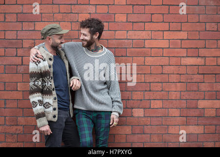 Gay paar kuscheln und lachen vor Backsteinmauer Stockfoto