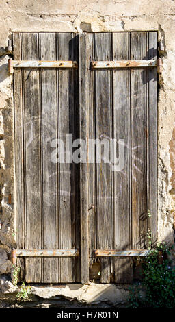 Eine verwitterte alte Holztür in einer notleidenden Wand Stockfoto