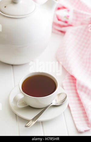 Eine Tasse schwarzen Tee und Teekanne auf weißen Tisch. Stockfoto