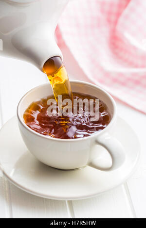 In einer Tasse Tee von Teekanne gießen. Stockfoto