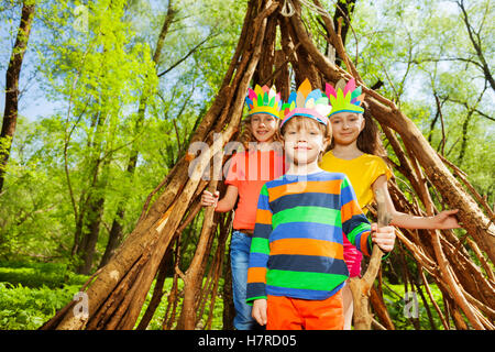 Drei glückliche Kinder spielen Injuns im Wald Stockfoto