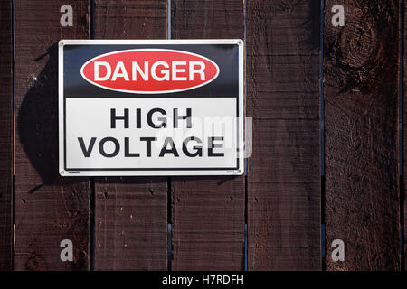 Hochspannung Warnschild am Holzzaun in einem Umspannwerk in Neuseeland Stockfoto