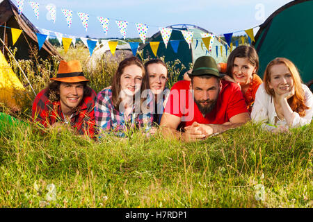 Glückliche Freunde liegen auf dem Rasen auf Campingplatz Stockfoto