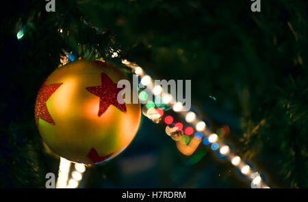 Goldenes Spielzeug Weihnachtskugel und elektrische Girlanden am Weihnachtsbaum Stockfoto