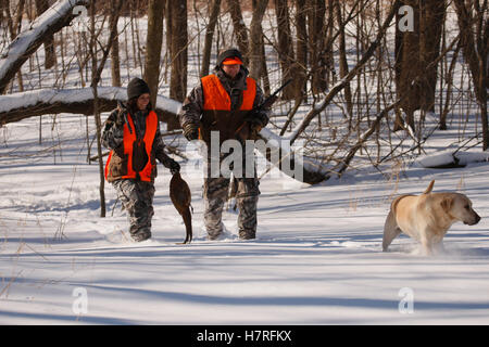 Männlichen und weiblichen Fasan Jäger im Winter mit gelben Labrador Stockfoto